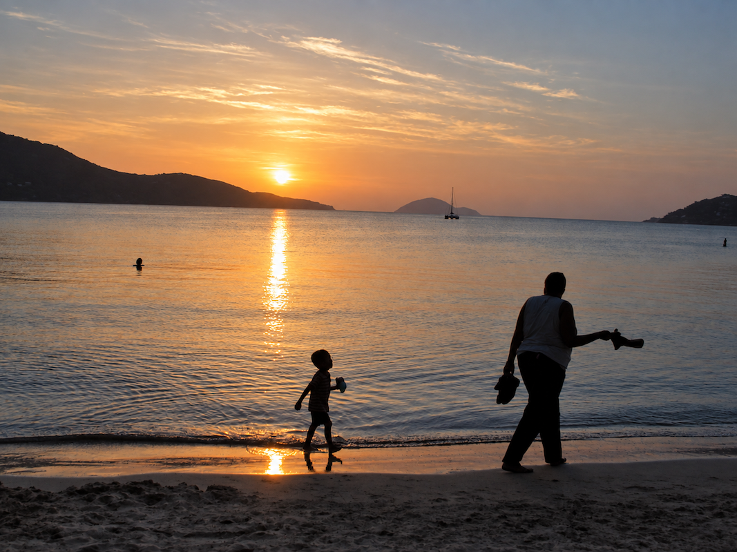 People walking along the beach at sunset in St. Thomas