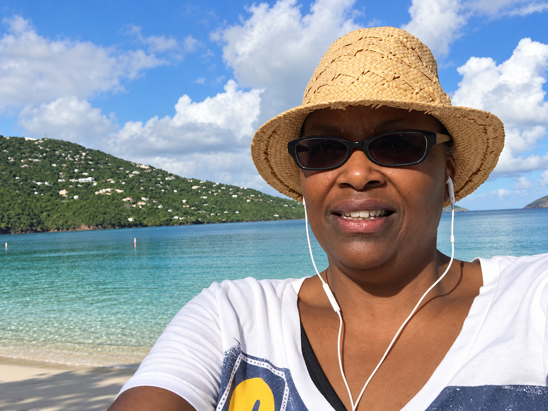 Edie Clarke smiling on a beach in St. Thomas wearing a sun hat